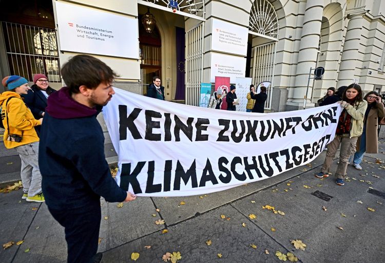 Protest vor dem österreichischen Bundesministerium: Mehrere Personen halten ein großes Banner mit der Aufschrift 