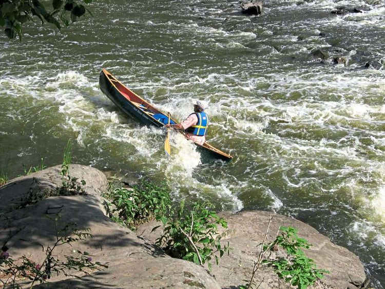 Ein Mann im Kanu in einem aufgewühlten Wasser.