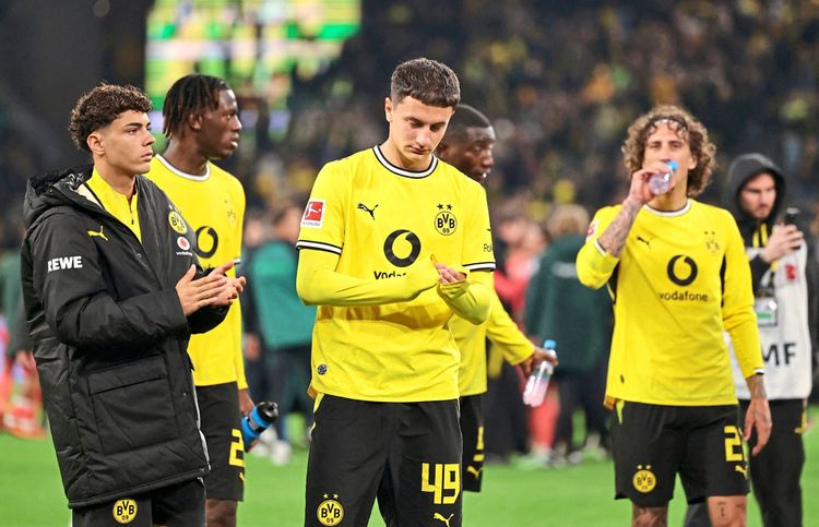 Spieler von Borussia Dortmund, gekleidet in gelbe Trikots, stehen nach einem Spiel im Signal Iduna Park in Dortmund. Einige Spieler klatschen, während andere Wasserflaschen halten oder trinken.