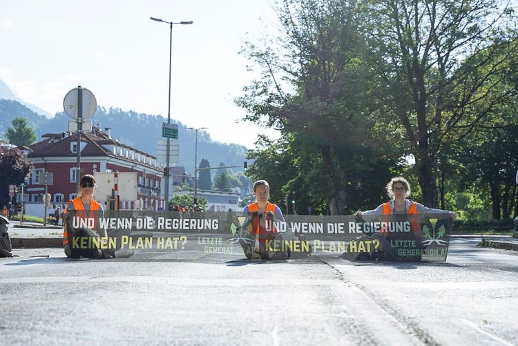 Drei Aktivistinnen bei einer Sitzblockade auf einer Straße