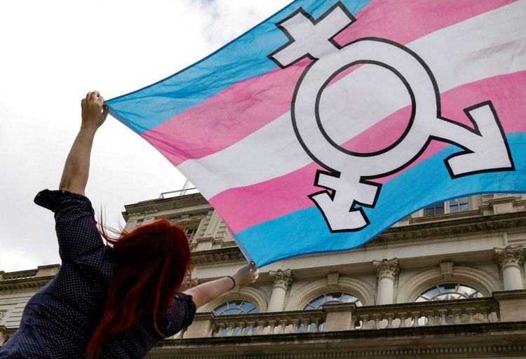 Transgender-Flagge weht im Wind, gehalten von einer Frau