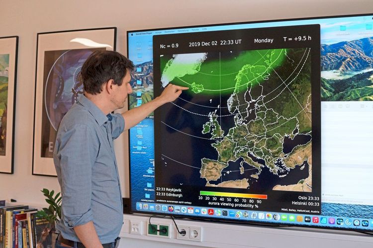 Forscher Christian Möstl steht vor einem Bildschirm, auf dem eine Landkarte Europas mit wissenschaftlichen Parametern abgebildet ist.