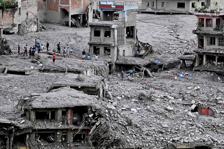 Menschen durchsuchen Trümmer und beschädigte Gebäude nach verwertbaren Materialien nach Überschwemmungen im Trishuli-Zentrum im Bezirk Nuwakot, Nepal. Die Überschwemmungen wurden durch einen Gletscherkollaps ausgelöst. Die Umgebung ist von Schlamm, Schutt und zerstörten Häusern geprägt.