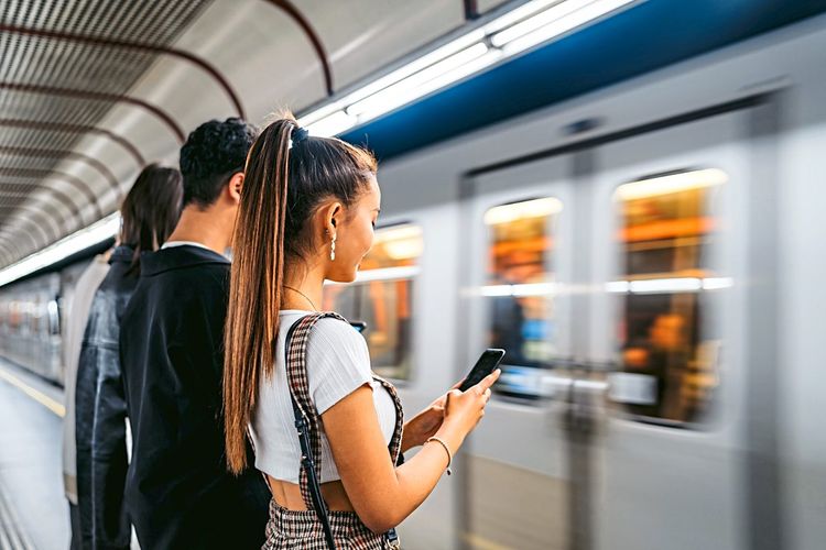 Teenager schauen in der U-Bahn-Station auf ihre Smartphones