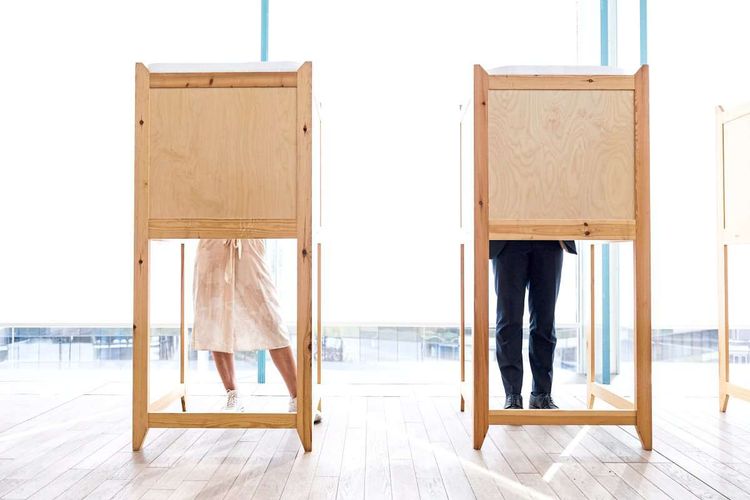 Frau (links) und Mann (rechts) bei der Stimmabgabe in einer Wahlkabine.