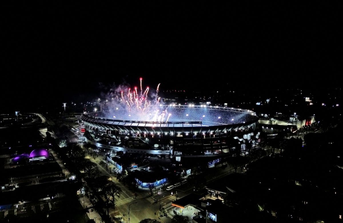 Drohnenaufnahme eines beleuchteten Stadions bei Nacht mit Feuerwerk am Himmel während einer Feier.