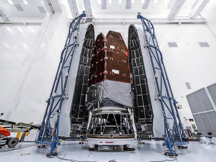 Das Bild zeigt das Nancy Grace Roman Space Telescope in der Payload Hazardous Servicing Facility am Kennedy Space Center der NASA in Florida. Die Raumsonde wird in ihrer Nutzlastverkleidung eingekapselt, um sie während des Rollouts, des Aufstiegs und der frühen Flugphasen zu schützen. Das Teleskop ist von geöffneter Verkleidung und technischen Vorrichtungen umgeben. Diese Vorbereitung erfolgt vor dem Start mit einer SpaceX Falcon Heavy Rakete.