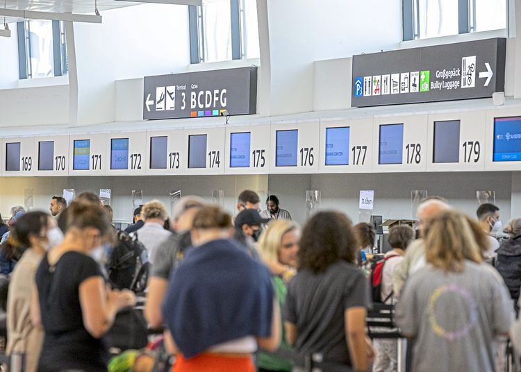 Reisende in Warteschlangen beim Check-in am Flughafen Wien