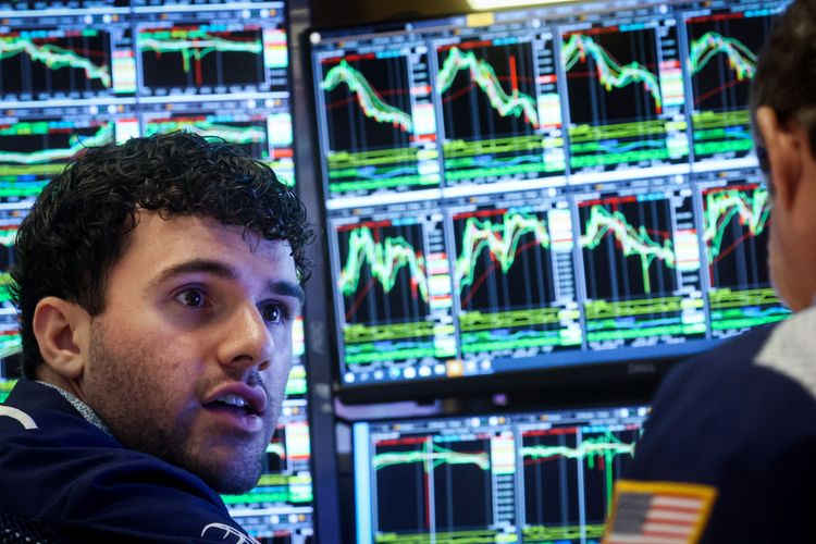 Ein Händler sitzt an der New Yorker Börse vor mehreren Bildschirmen. Die Charts, die zu sehen sind, zeigen Kurse die rauf- und runter gehen.