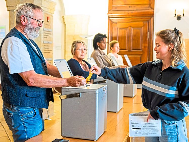 Eine Frau gibt während der Wahlen in der Schweiz ihren Stimmzettel ab.