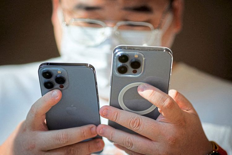Ein Mann betrachtet zwei iPhone-14-Modelle in einem Laden in Peking