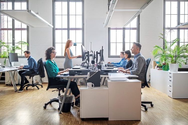 Menschen arbeiten in einem hellen und offenen Büro an ihren Schreibtischen