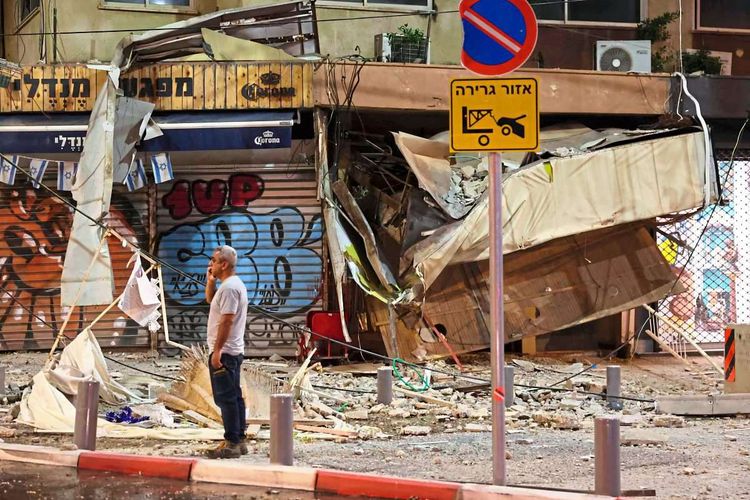 Ein Mann steht in Tel Aviv auf der Straße vor einem zerstörten Geschäft, das von einer Hamas-Rakete getroffen worden ist.