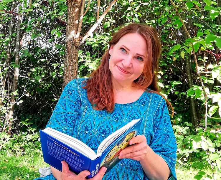 Kornelia Rümmele-Gstrein mit Buch im Garten sitzend.