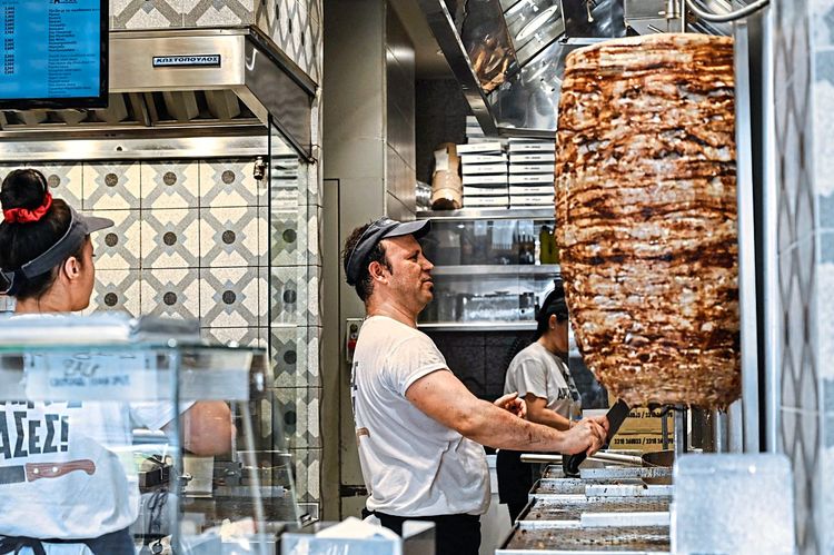 Ein Mann schneidet Fleisch von einem Döner-Kebab-Spieß
