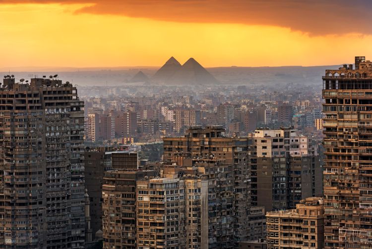 Dreht man sich aber um, wirkt die ganze Szene schon etwas ernüchternder – liegen die Monumente doch direkt am wenig attraktiven Stadtrand der ägyptischen Hauptstadt Kairo.