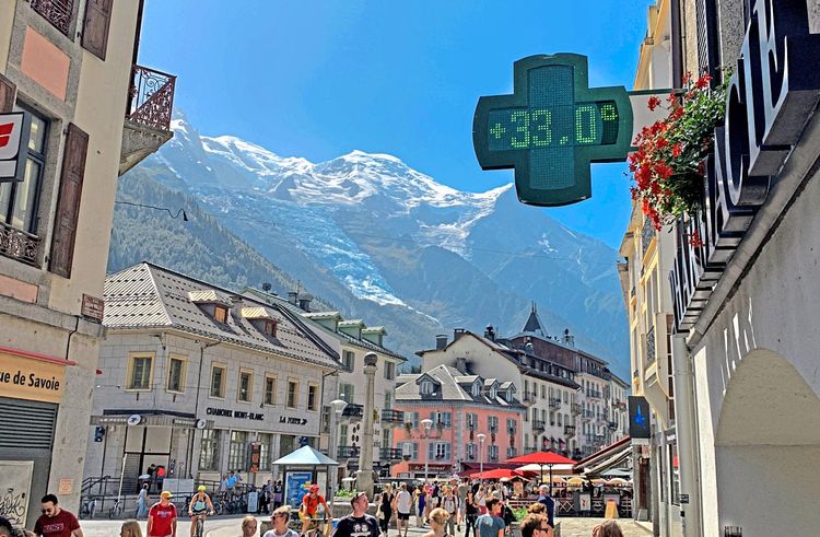 Ein kreuzförmiges Display einer Apotheke in Chamonix, Frankreich, zeigt eine Temperatur von 33 Grad Celsius. Im Hintergrund ist der Mont Blanc zu sehen. Aufgenommen am 23. August 2023.