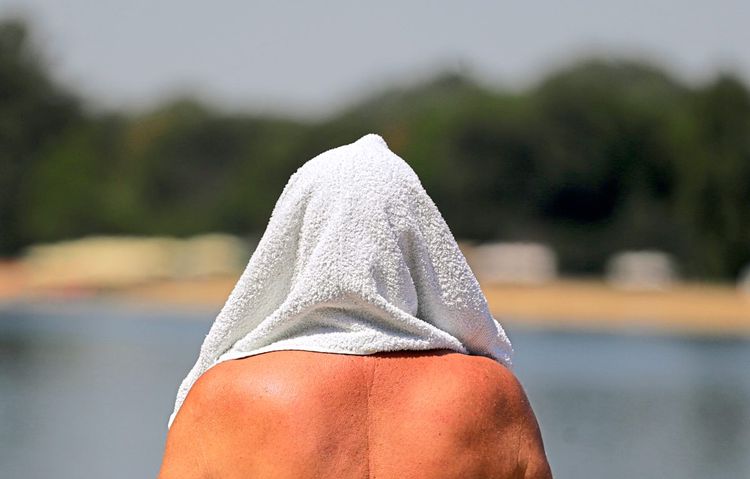 Mann mit Handtuch auf dem Kopf, von hinten fotografiert (Symboldbild)