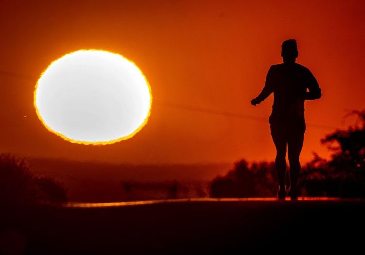Eine Person läuft der Sonne entgegen.