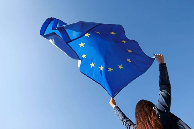 Frau hält EU Flagge hoch.