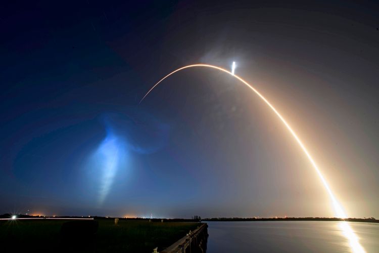 Eine Langzeitbelichtung zeigt den Start einer SpaceX Falcon 9-Rakete am 9. Juli 2026 in Cape Canaveral, Florida. Die Flugbahn der Rakete bildet eine leuchtende Kurve gegen den nächtlichen Himmel, begleitet von einer bläulichen Wolke durch den Abgasausstoß. Der Startplatz liegt in der unteren Bildhälfte nahe einem Gewässer.