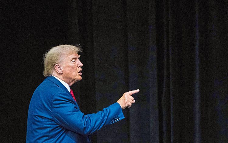 Trump im Profil vor schwarzem Hintergrund, er zeigt mit dem Finger auf eine nicht abgebildete Person