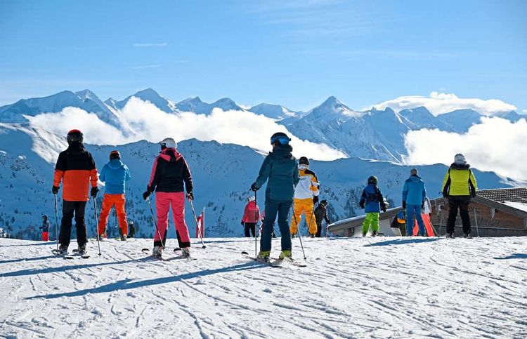 Skifahrer in bunter Kleidung vor einer Bergkulisse