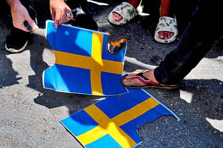 Schwedens Fahnen auf der Straße, jemand zündet sie an.