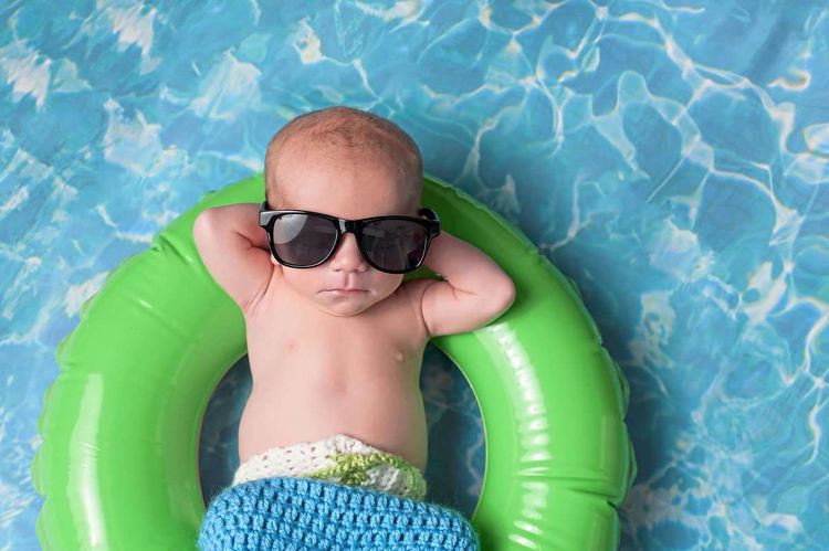 Ein Säugling mit Sonnenbrille liegt in einem Schwimmreifen.