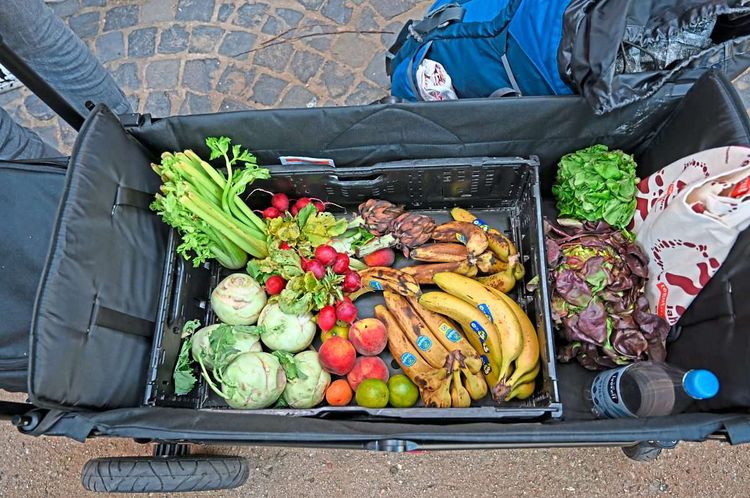 In einem Fahrrad-Anhänger liegt Obst und Gemüse.