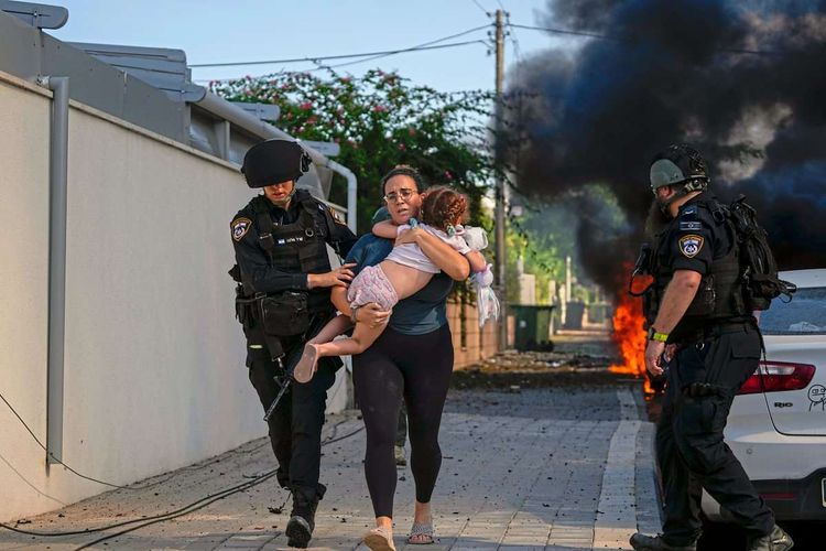 Polizisten schützen eine flüchtende Frau und ihr Kind.