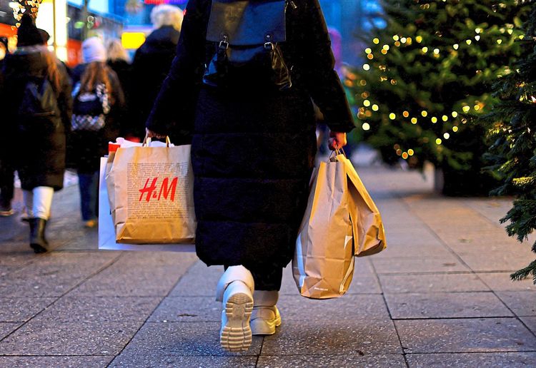 Frau mit Einkaufstaschen auf weihnachtlich geschmückter Straße