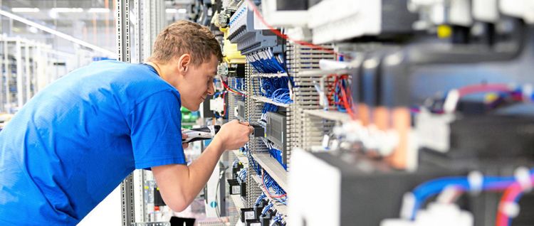 Junger Mann in Industriefirma arbeitet an elektronischem Gerät