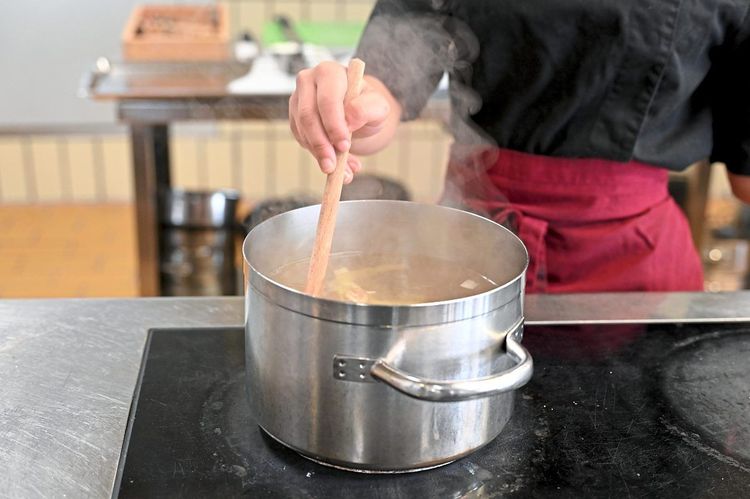Auszubildende rührt in einem Suppentopf in der Lehrküche der Berufsschule für Gastgewerbe