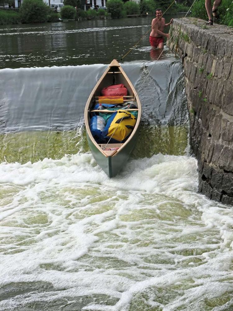 Ein Kanu, wie es über eine Schwelle geführt wird.