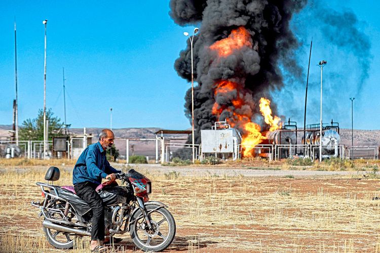 Ein Mann auf dem Motorrad in der Nähe eines Feuers, das am 5. Oktober 2023 in der Zarba-Ölanlage in al-Qahtaniyah im Nordosten Syriens nahe der türkischen Grenze wütet.
