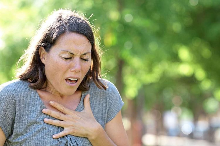 Herzinfarkt – Frau mittleren Alters greift sich an die Brust