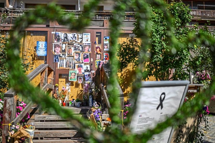Eine improvisierte Gedenkstätte vor der Constellation-Bar in Crans-Montana, Schweiz, in Erinnerung an die Opfer eines verheerenden Feuers in der Neujahrsnacht. Fotos der Verstorbenen und Blumenarrangements sind aufgestellt.