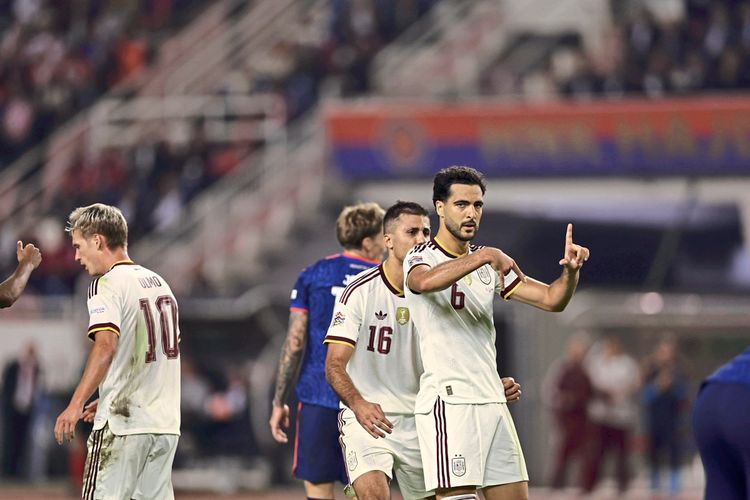 Spanische Fußballspieler in weißen Trikots feiern ein Tor während eines Nations-League-Spiels zwischen Kroatien und Spanien. Im Vordergrund hebt ein Spieler die Hand zum Jubel. Hintergrund mit unscharfem Publikum und Spielfeld.