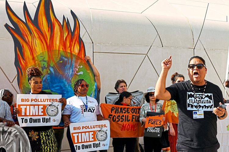 Mehrere Demonstrantinnen und Demonstranten halten Schilder hoch und protestieren in Dubai gegen die weitere Förderung fossiler Brennstoffe.