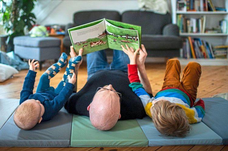 Ein Vater liest seinen Kindern ein Buch vor.