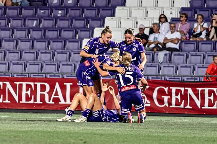 Spielszene aus der Frauen-Bundesliga am 3. Spieltag (14.08.2026): Spielerinnen eines Teams in lila Trikots feiern ein Tor auf dem Spielfeld, umringt von jubelnden Mitspielerinnen. Im Hintergrund eine Tribüne mit Zuschauern.