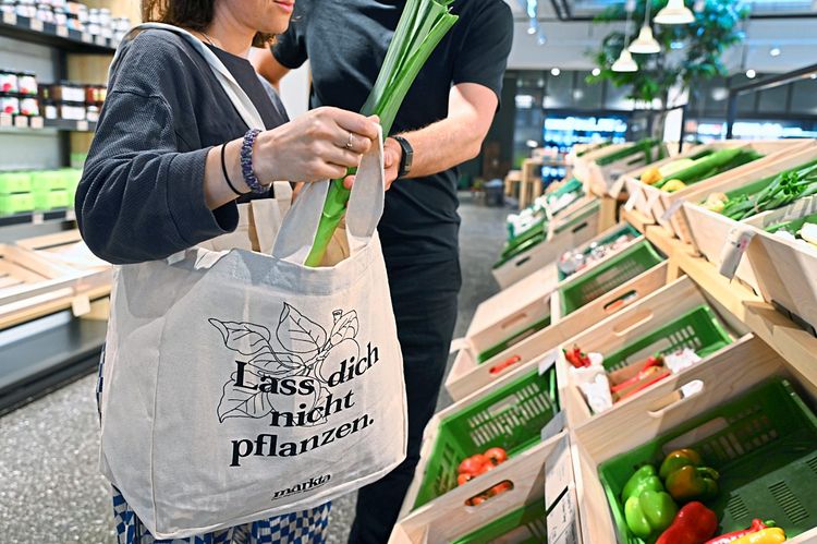 Zwei Personen vor dem Gemüseregal, die Lebensmittel in die Stofftasche geben. 