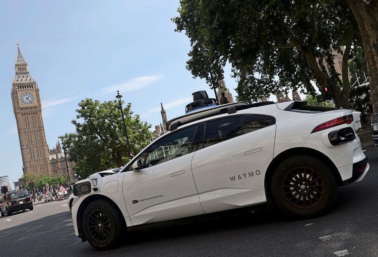 Ein autonomes Fahrzeug von Waymo fährt neben dem Elizabeth Tower (auch bekannt als Big Ben) und den Houses of Parliament in London. Das Auto wird im Rahmen von Tests und Kartierungseinsätzen genutzt.