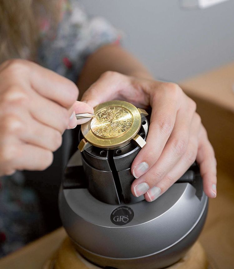 Eine Person arbeitet an der Gravur eines Stückes aus Gold