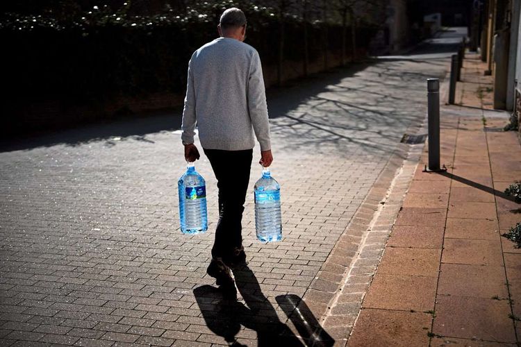 Ein Mann trägt zwei Wasserflaschen.