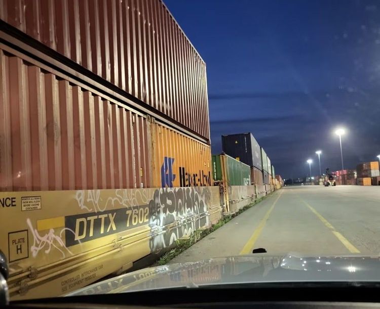 Foto aus einem Polizeiwagen, das Container an einem Frachtbahnhof zeigt.
