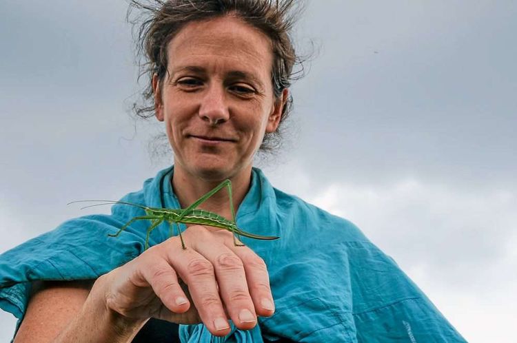 Ökologin Irene Drozdowski hält eine Heuschrecke auf der Hand