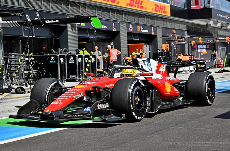 Ferrari-Formel-1-Auto mit der Startnummer 44 fährt durch die Boxengasse beim Großen Preis von Ungarn auf dem Hungaroring. Im Hintergrund sind Boxencrew-Mitglieder, Werkzeuge und Garagen zu sehen.