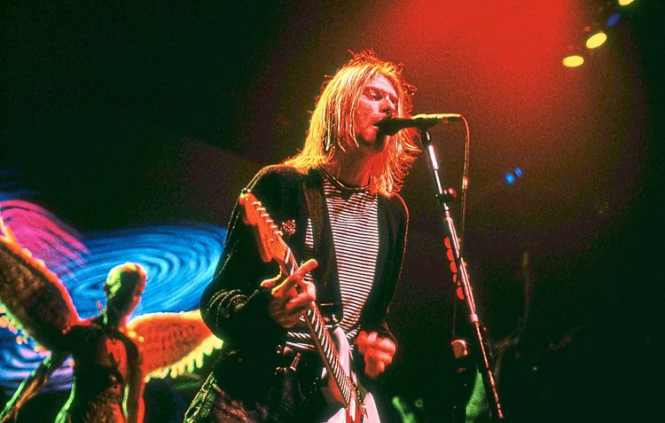 Kurt Cobain bei einem Nirvana-Konzert, im Hintergrund der Engel des 